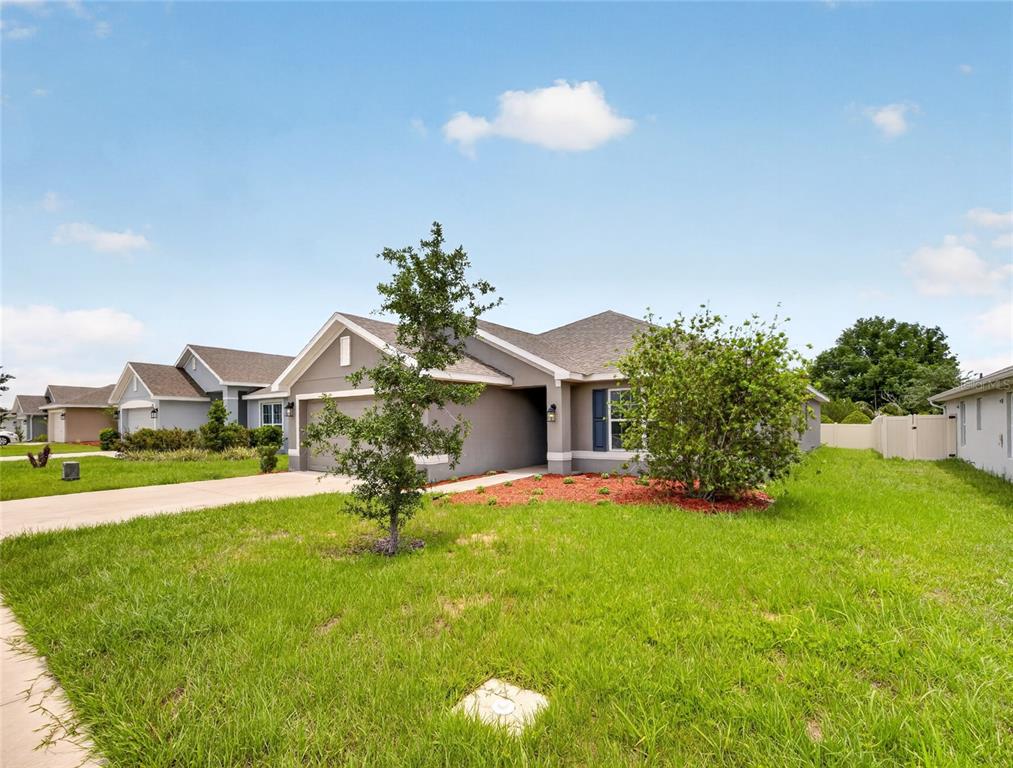 A single-story suburban house with a gray exterior, a concrete driveway, and a front lawn — 1113 CITRUS LANDINGS BOULEVARD, DAVENPORT, FL