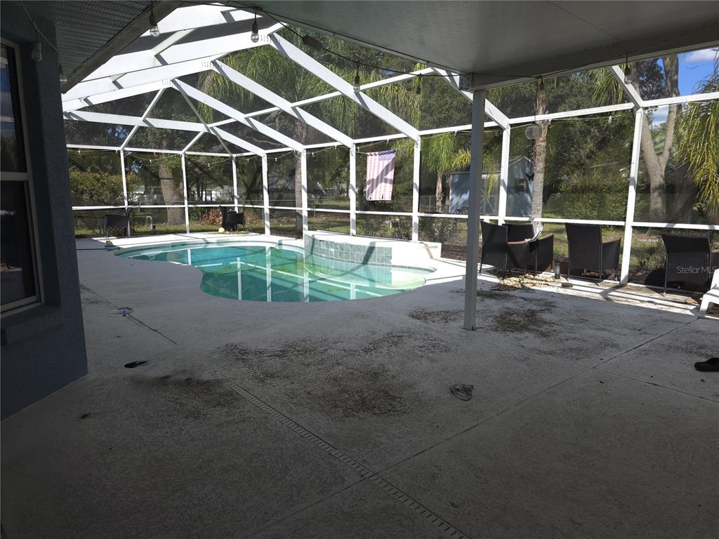 A screened-in patio features a swimming pool with a tiled water feature and outdoor furniture — 11179 SW 61ST CIRCLE, OCALA, FL