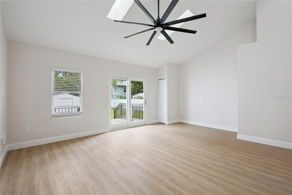 A living room with light wood-look flooring, a vaulted ceiling, and a sliding glass door — 201 E MURIEL STREET, ORLANDO, FL