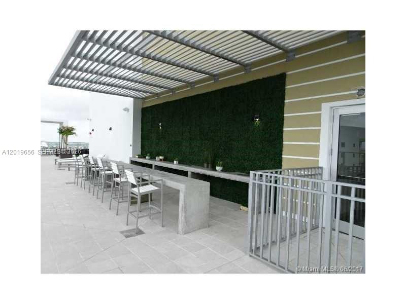 An outdoor patio features a long concrete bar, bar stools, and a green wall — 1010 SW 2nd Ave # 1105, Miami FL 33130, MIAMI, FL