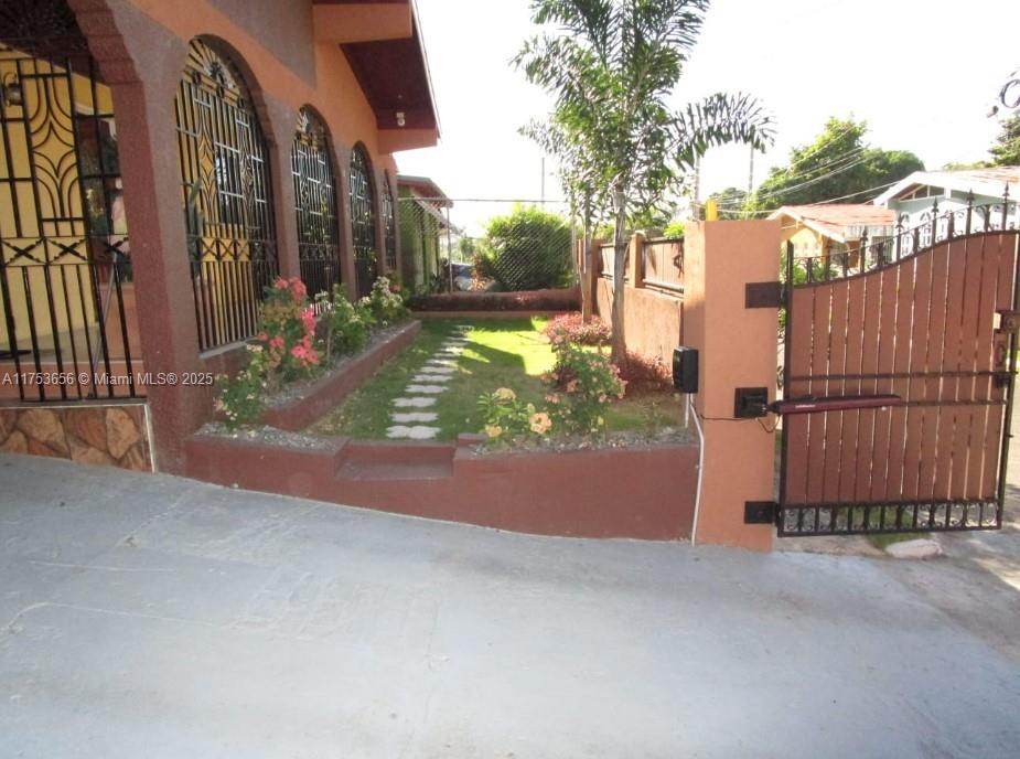 A paved driveway leads to a gated entrance and a small lawn with stone pavers — 00 Queensbury, Kingston, Jamaica, NA, NA