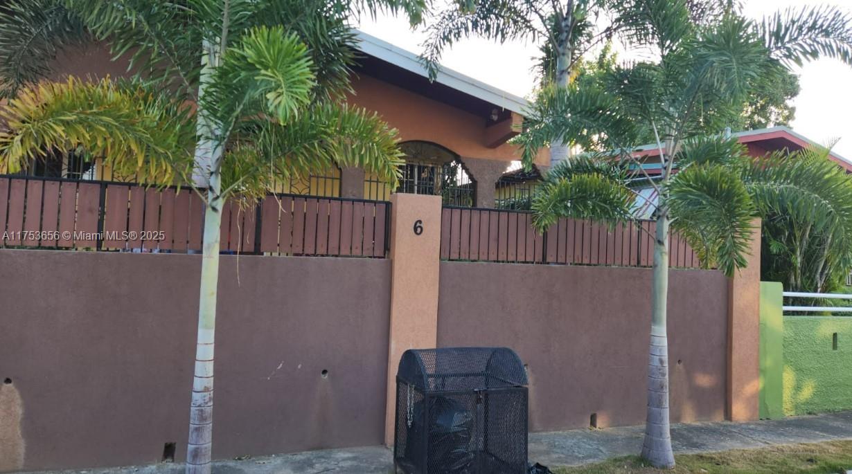 A brown concrete wall with a wooden fence sits in front of a house — 00 Queensbury, Kingston, Jamaica, NA, NA