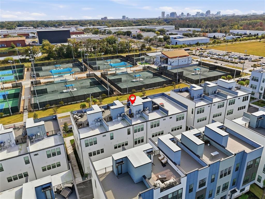 An aerial view shows modern townhomes with rooftop terraces located next to outdoor tennis courts — 2038 PACKING DISTRICT WAY, ORLANDO, FL