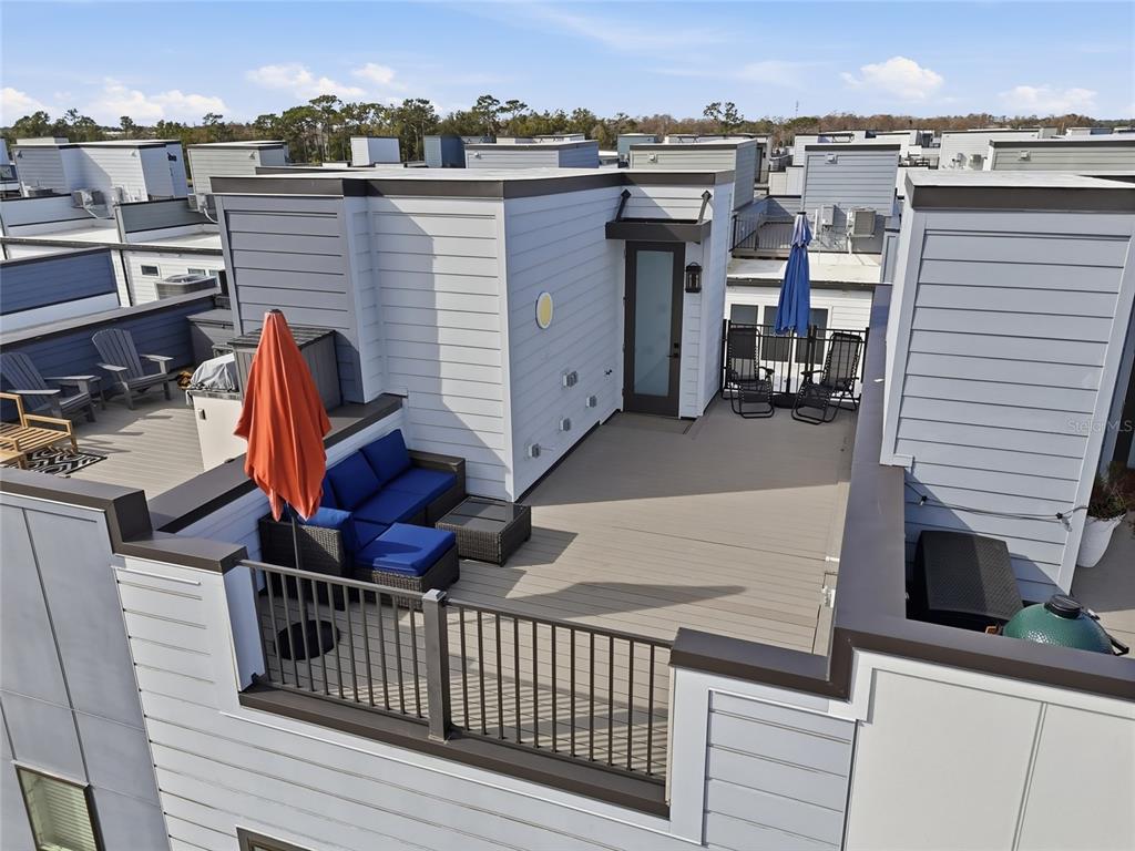 An elevated rooftop deck features a seating area with blue cushions and an orange umbrella — 2038 PACKING DISTRICT WAY, ORLANDO, FL