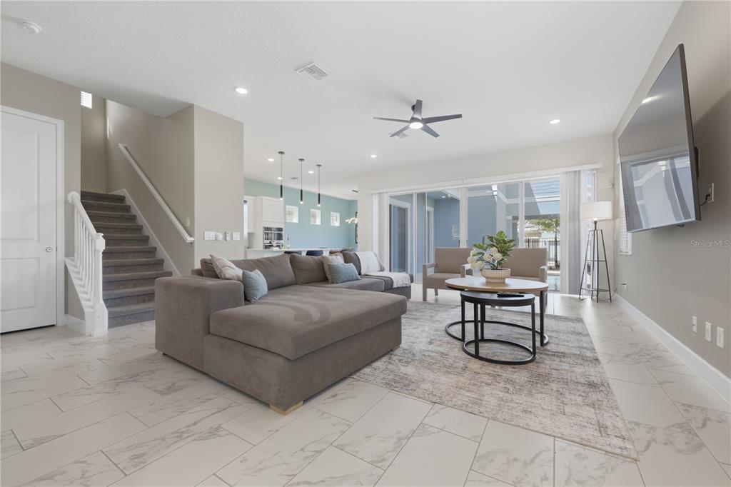 A living room with a gray sectional, tile flooring, and stairs leading to an upper level — 1428 REUNION BOULEVARD, REUNION, FL