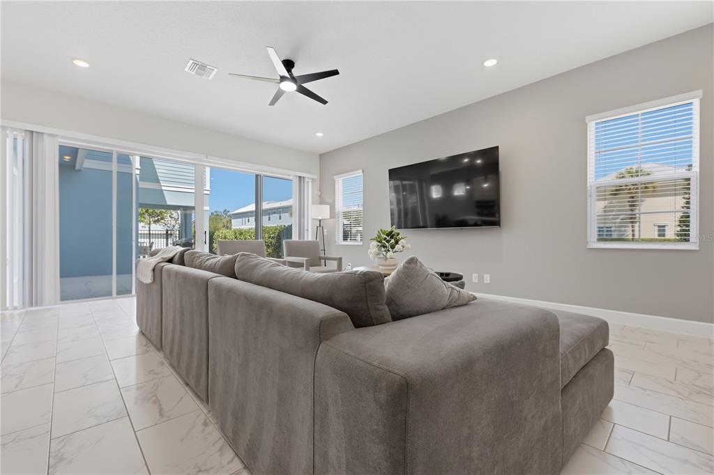 A living room features a large gray sectional sofa, tile flooring, and a wall-mounted television — 1428 REUNION BOULEVARD, REUNION, FL