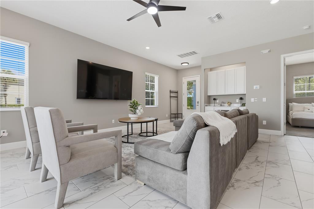 A living room features gray furniture, a wall-mounted television, and white tile flooring — 1428 REUNION BOULEVARD, REUNION, FL