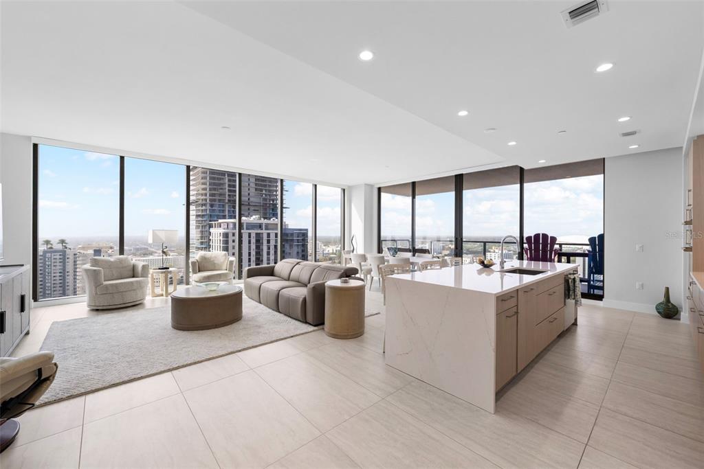 A modern open-concept living area with a kitchen island, floor-to-ceiling windows, and city views — 275 1ST AVENUE S UNIT 2206, ST PETERSBURG, FL