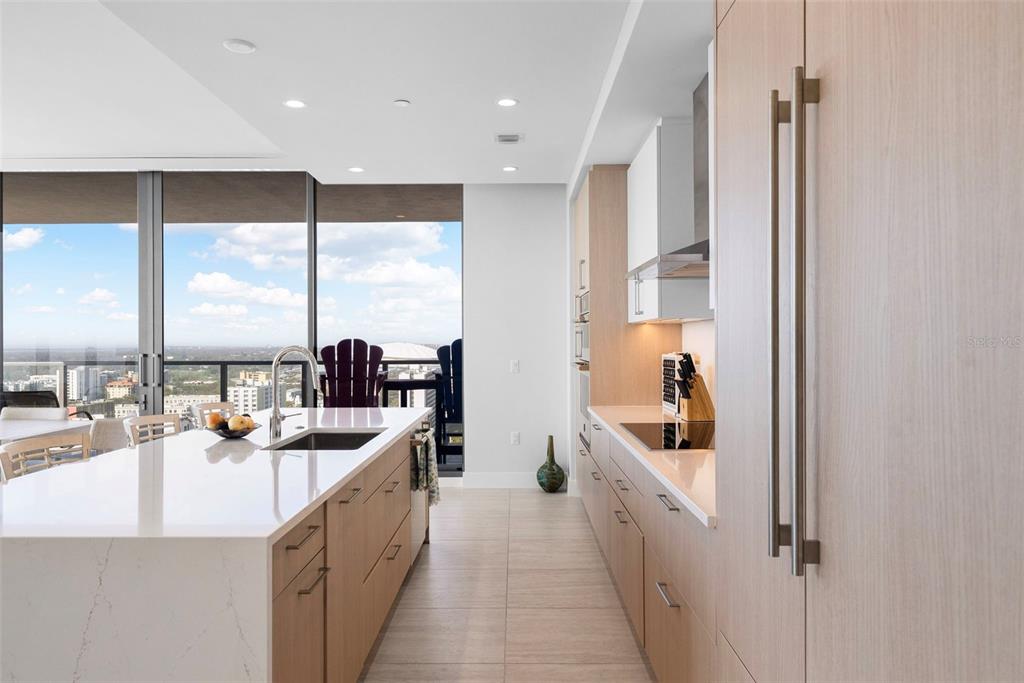 A modern kitchen features light wood cabinetry, a white quartz island, and floor-to-ceiling windows — 275 1ST AVENUE S UNIT 2206, ST PETERSBURG, FL