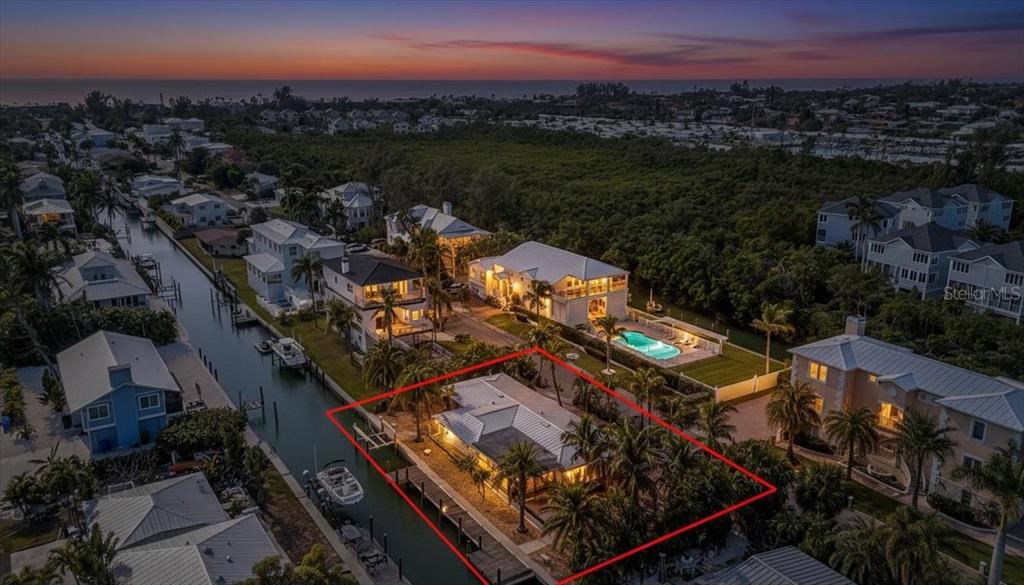 An aerial view shows a waterfront house with a private dock at sunset — 834 JUNGLE QUEEN WAY, LONGBOAT KEY, FL