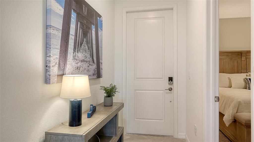 A hallway features a console table with a lamp, wall art, and a closed white door — 12180 WELLEN GOLF STREET UNIT 202, VENICE, FL