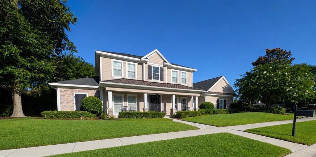 A two-story suburban house with tan siding, a stone facade, and a covered front porch — 5650 KILLIANS PATH, WESLEY CHAPEL, FL