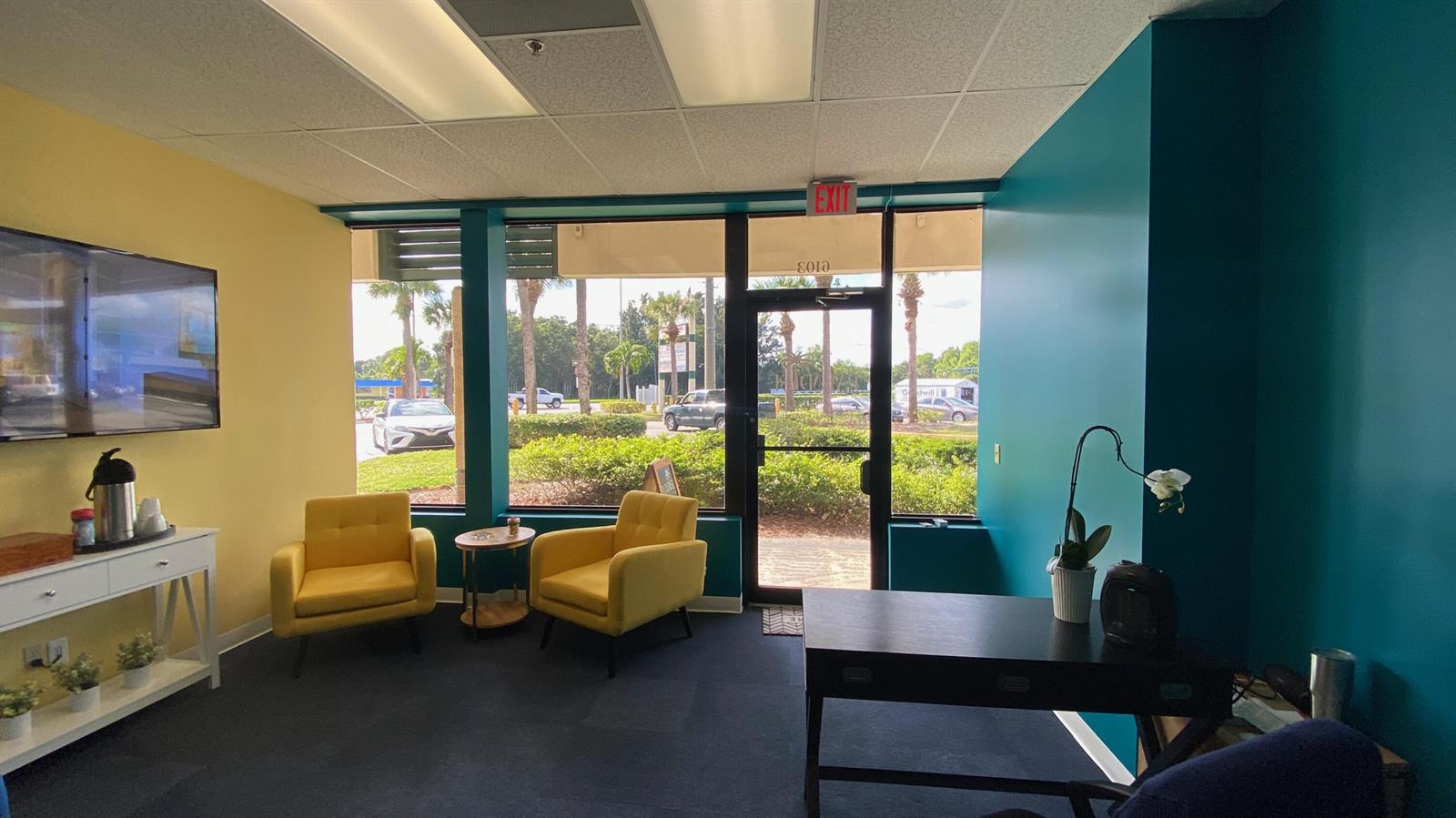 A waiting area features two yellow armchairs, a dark desk, and a large glass door — 6103 SE Federal Highway, Stuart FL 34997, STUART, FL