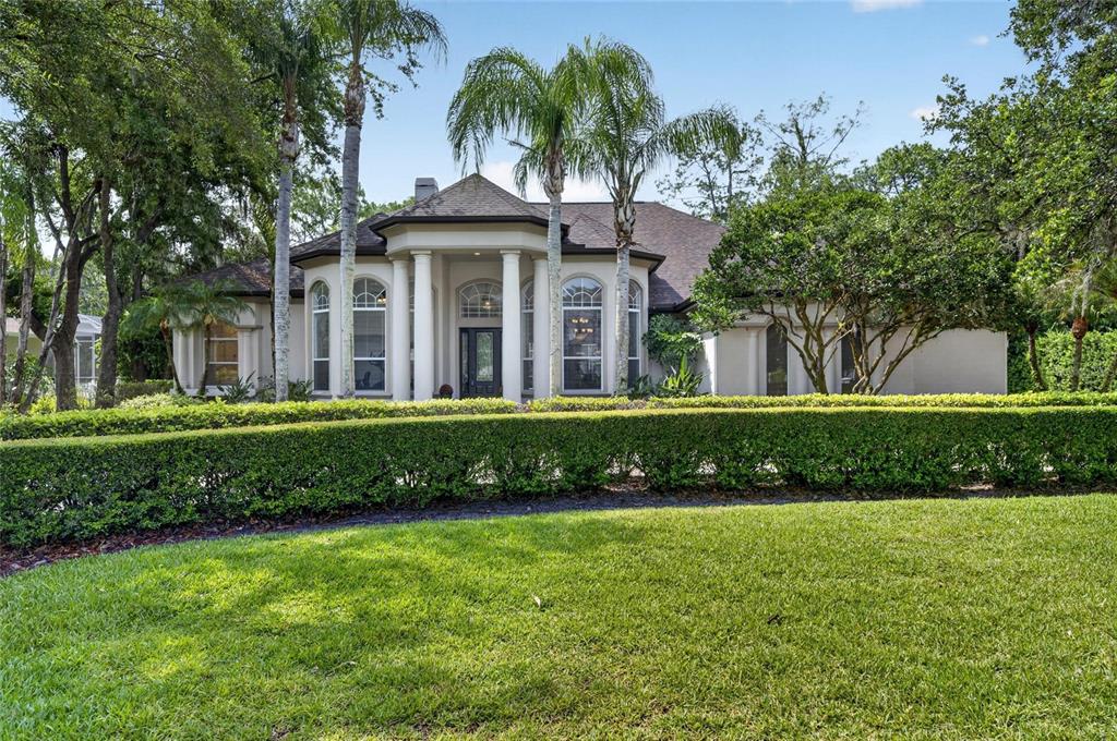A single-story house with a columned entryway, arched windows, and a manicured hedge in front — 6353 W MACLAURIN DRIVE, TAMPA, FL