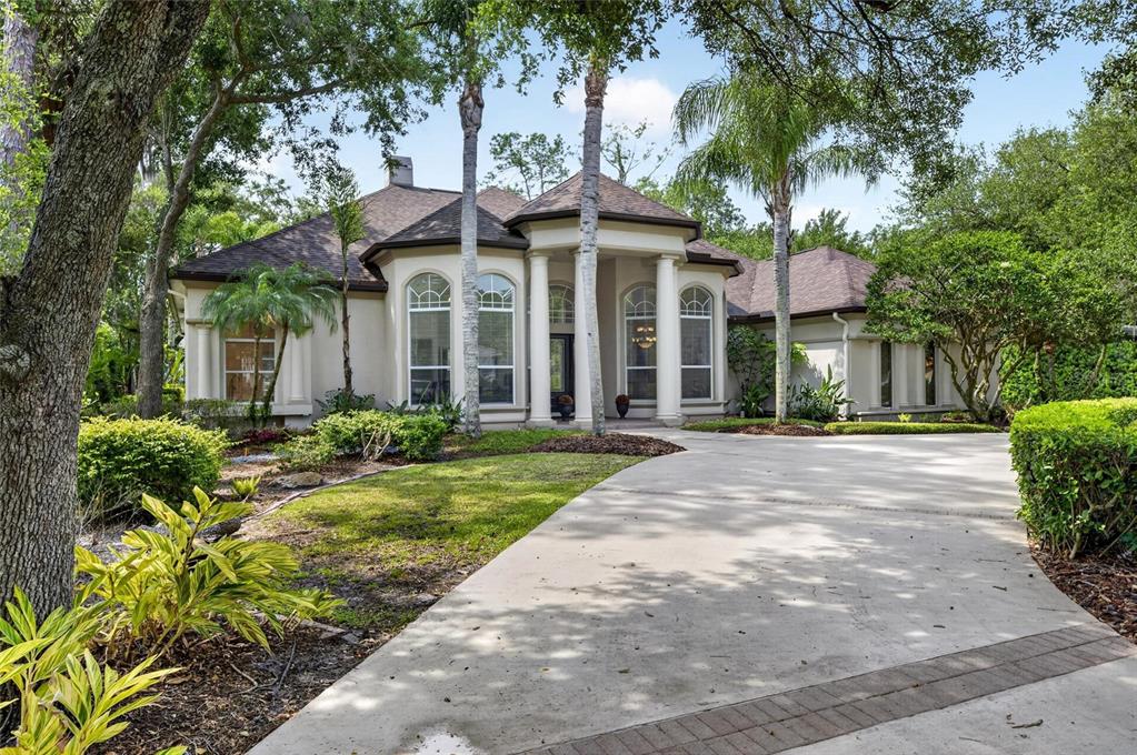 A single-story house with a columned entryway, arched windows, and a concrete driveway — 6353 W MACLAURIN DRIVE, TAMPA, FL