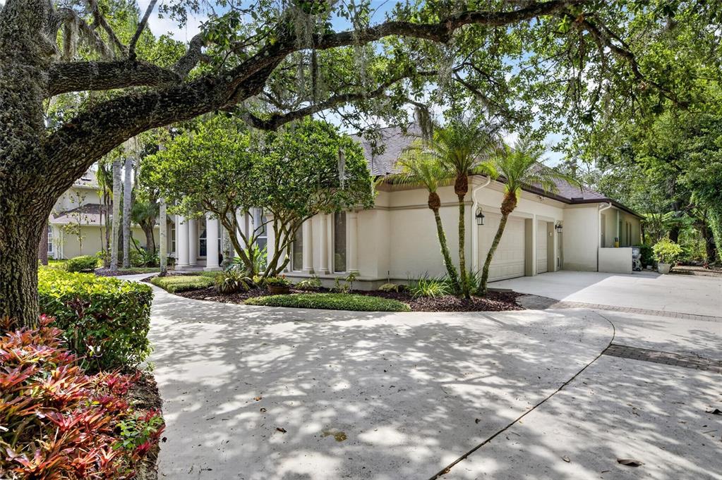 A concrete driveway leads to a house with a multi-car garage and landscaped front yard — 6353 W MACLAURIN DRIVE, TAMPA, FL