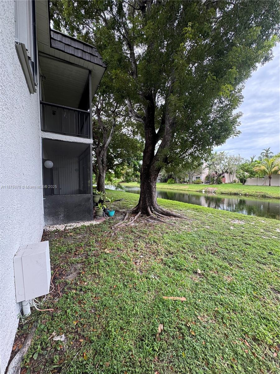 A two-story screened patio overlooks a grassy yard with a large tree and a canal — 10353 N Kendall Dr, Miami FL 33176, MIAMI, FL
