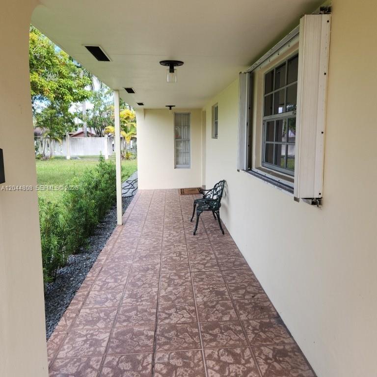 A covered outdoor patio features tiled flooring, a metal chair, and views of a yard — 11249 SW 169th St # V4831, Miami FL 33157, MIAMI, FL