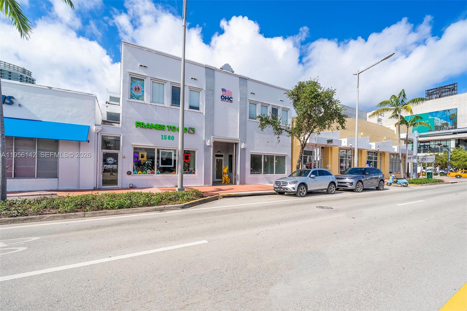 A two-story commercial building with a storefront and parked cars on a sunny street — 1558 Alton Rd, Miami Beach FL 33139, MIAMI BEACH, FL