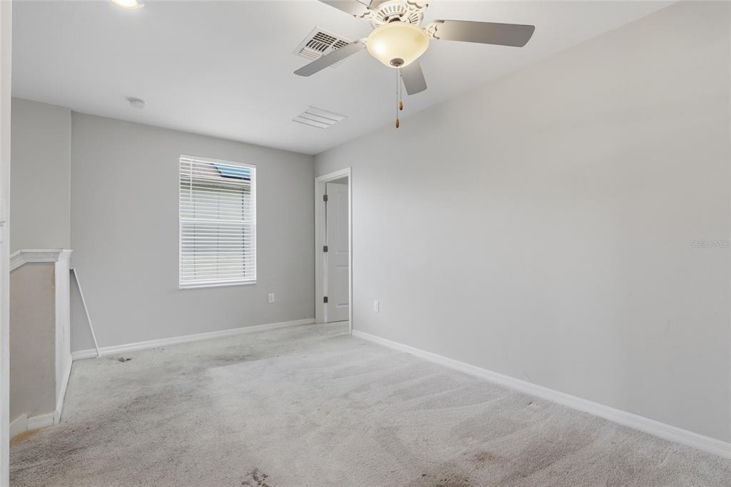 An empty bedroom features gray walls, beige carpeting, a ceiling fan, and a window — 17237 WHITE MANGROVE DRIVE, WIMAUMA, FL