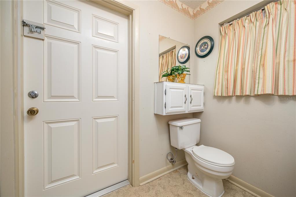 A small bathroom features a white toilet, wall-mounted cabinet, mirror, and a door — 41 SPRING LANE, HAINES CITY, FL