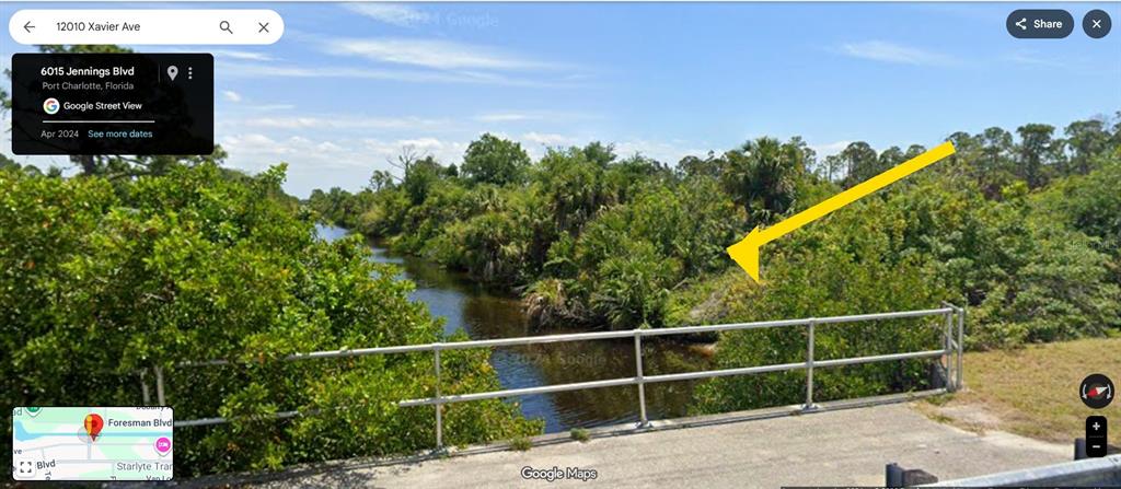 A view of a canal bordered by dense vegetation from a bridge with metal railings — 12010 XAVIER AVENUE, PORT CHARLOTTE, FL