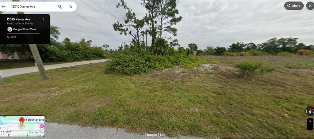 A vacant, grassy lot with scattered trees and shrubs under a cloudy sky — 12010 XAVIER AVENUE, PORT CHARLOTTE, FL