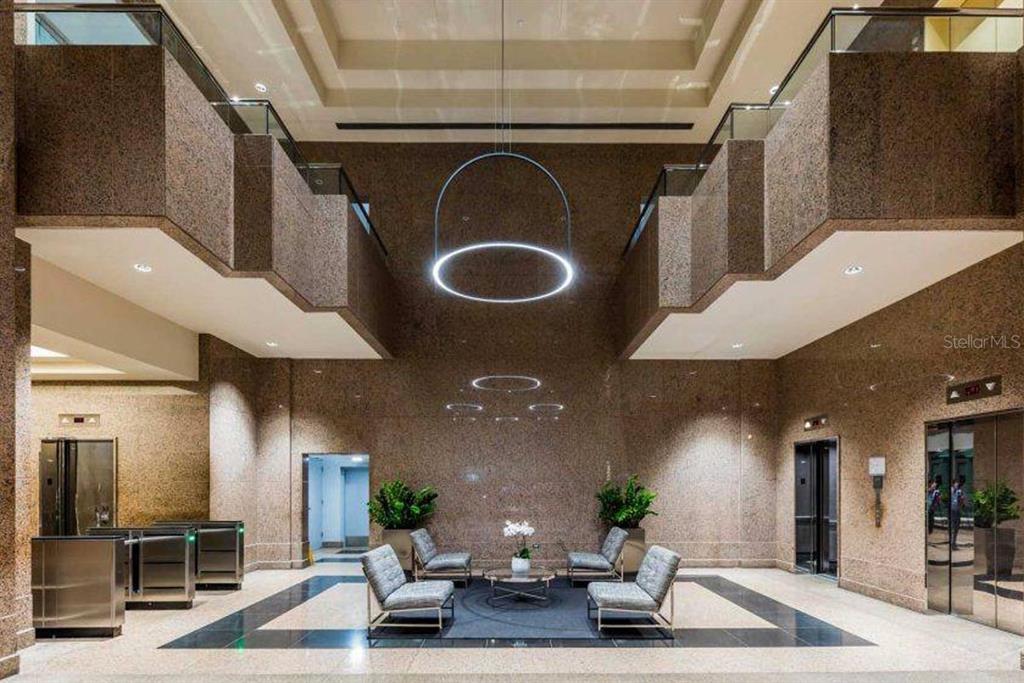 A modern building lobby features high ceilings, stone walls, elevators, and a central seating area — 270 MUÑOZ RIVERA, SAN JUAN, PR
