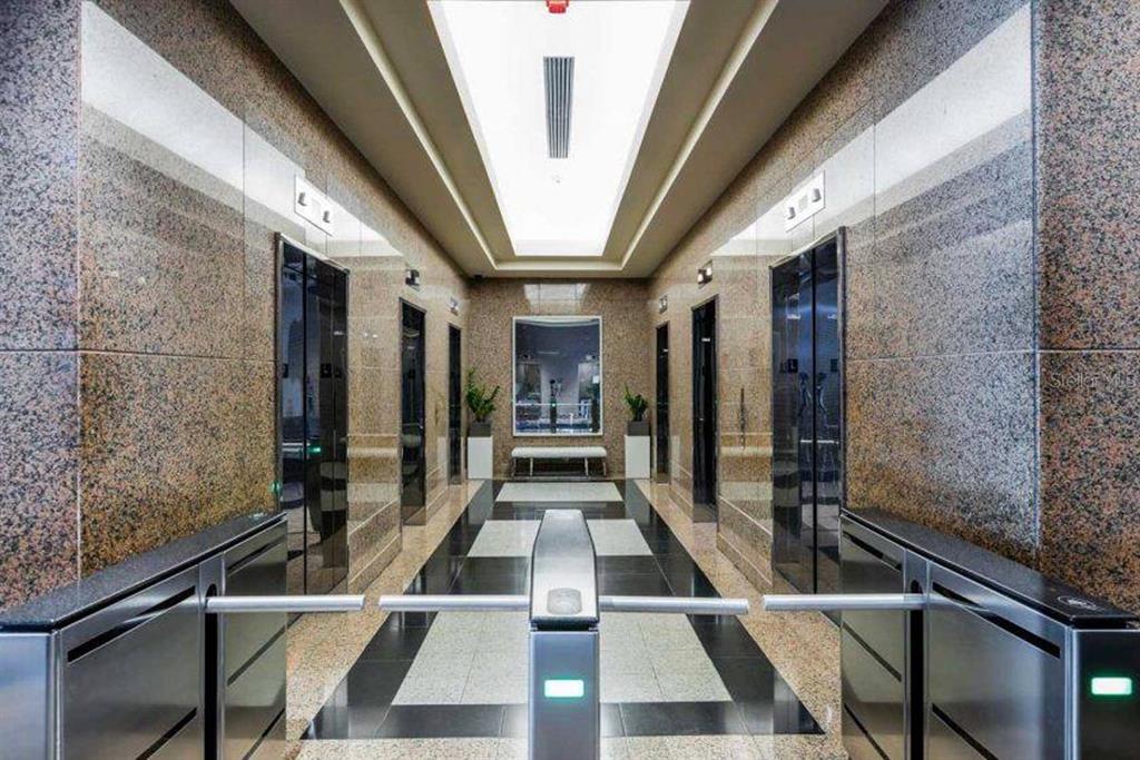 A modern building lobby features polished granite walls, elevator banks, and security turnstiles — 270 MUÑOZ RIVERA, SAN JUAN, PR