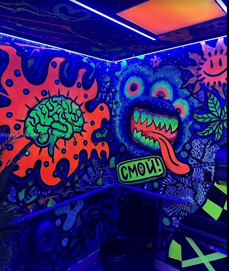 A small room features walls covered in vibrant, neon-colored graffiti art illuminated by black lights — MIAMI BEACH, FL