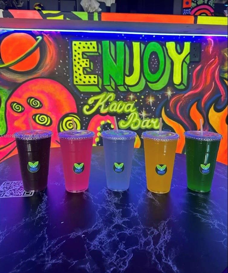 Five colorful drinks in plastic cups sit on a table in front of a mural — MIAMI BEACH, FL