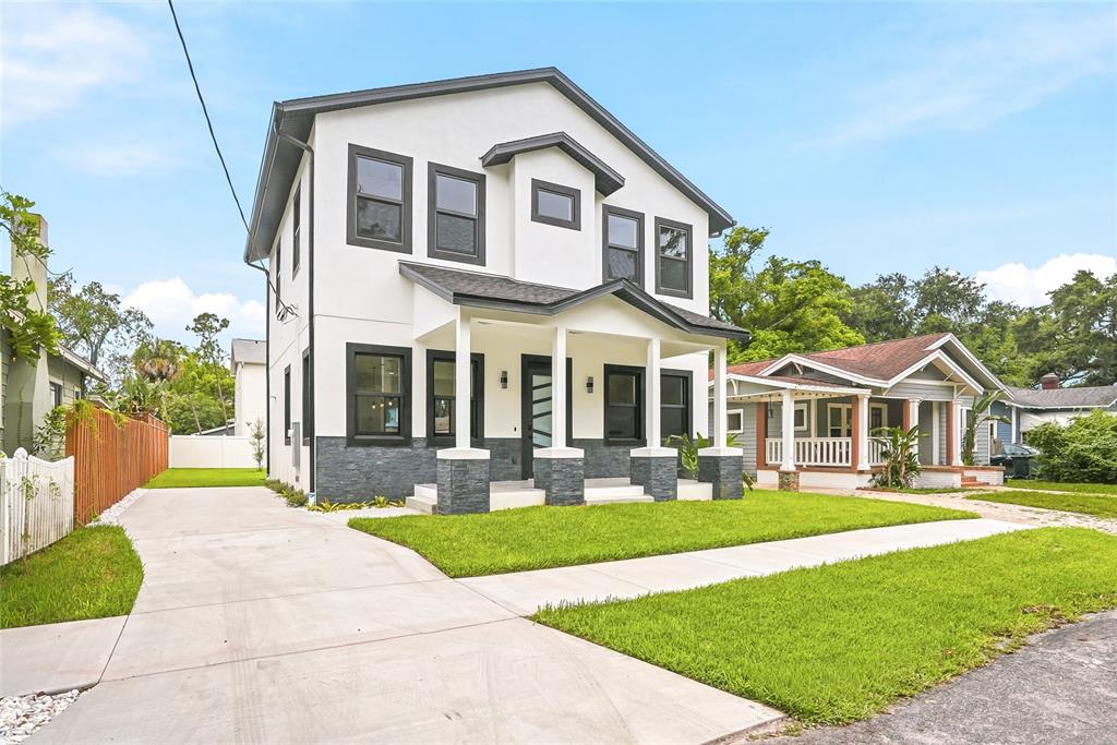 A modern house exterior features a covered porch with stone pillars and a glass-paneled door — 7106 N 10TH STREET, TAMPA, FL