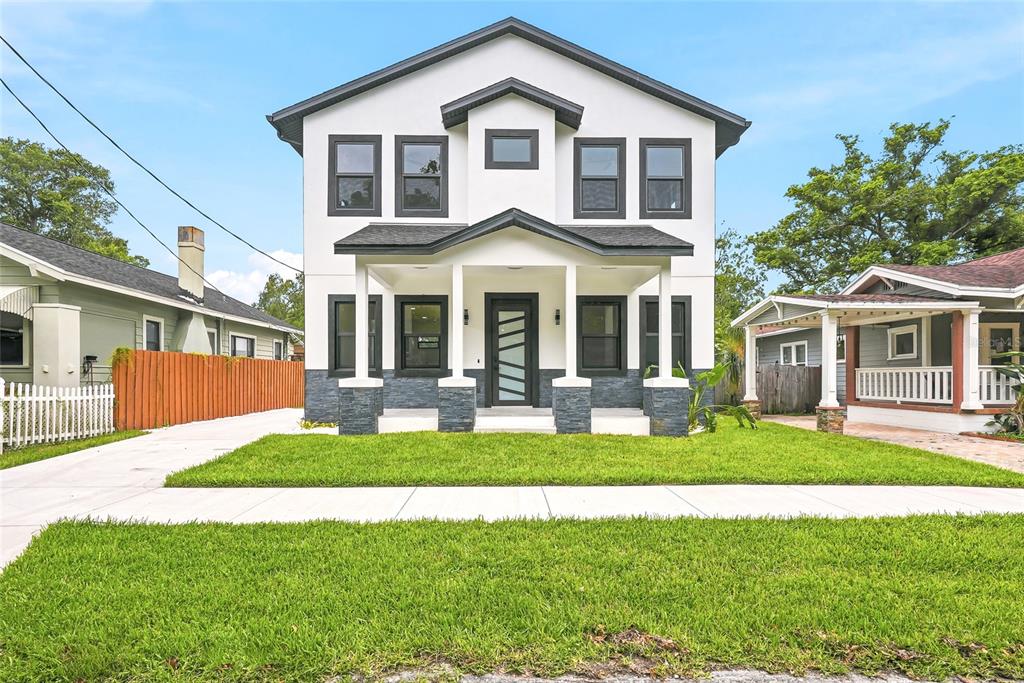 A covered front porch features stone veneer siding, white columns, and light-colored tile flooring — 7106 N 10TH STREET, TAMPA, FL