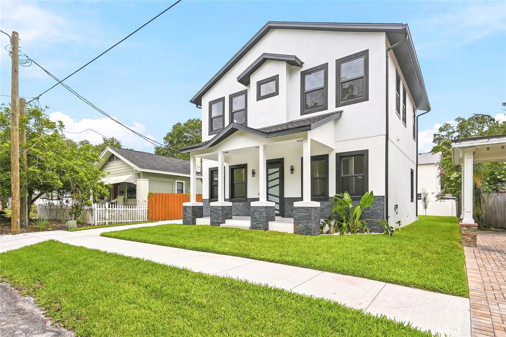 A modern front porch features gray stone siding, a glass-paneled door, and tiled flooring — 7106 N 10TH STREET, TAMPA, FL