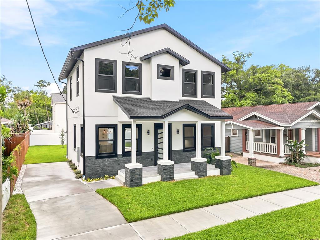 An empty room features white walls, light wood-look flooring, black-framed windows, and a modern door — 7106 N 10TH STREET, TAMPA, FL