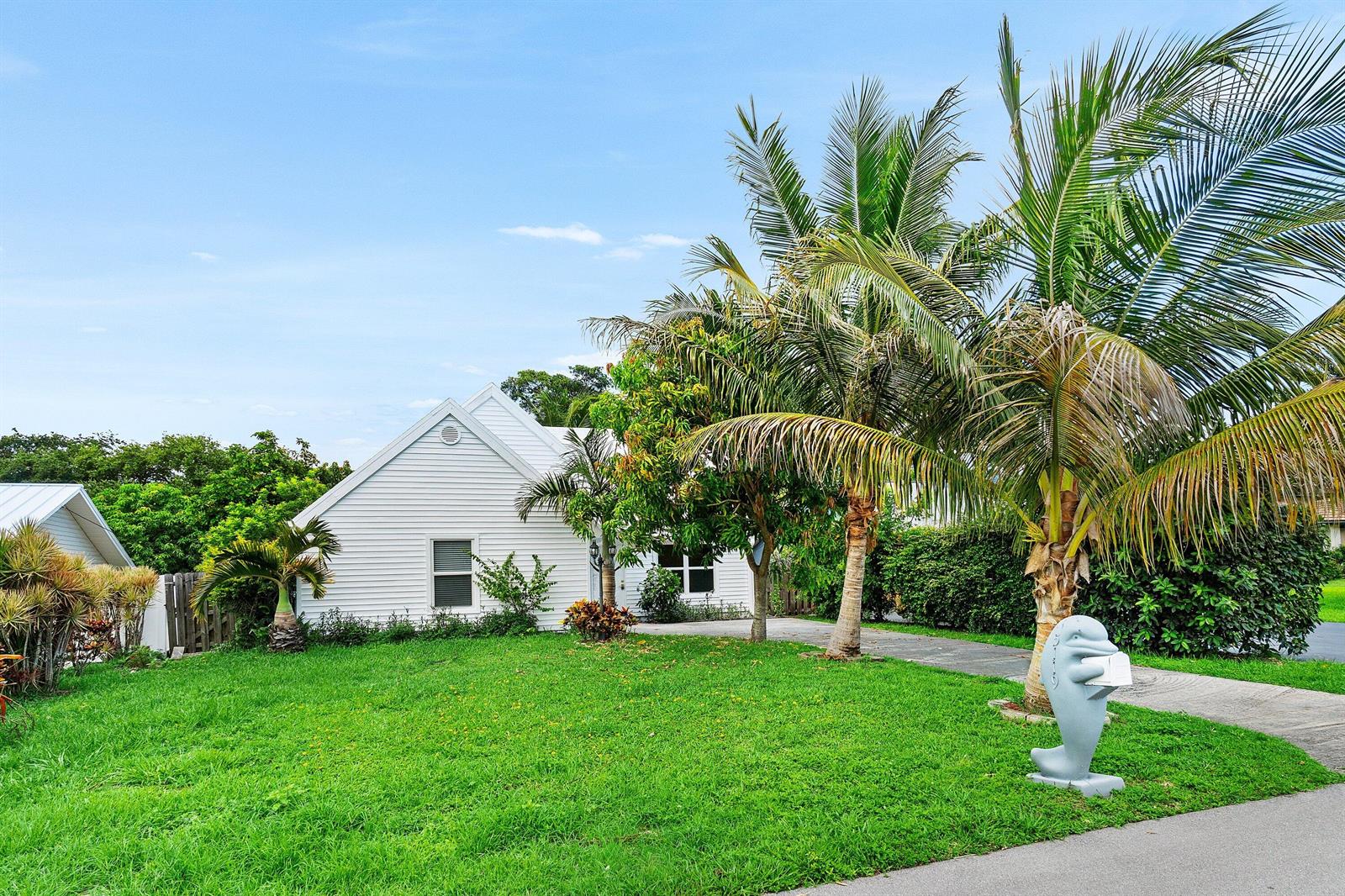 A white house with a green lawn, palm trees, and a dolphin-shaped mailbox — 5119 Oak Hill Road, Delray Beach FL 33484, DELRAY BEACH, FL