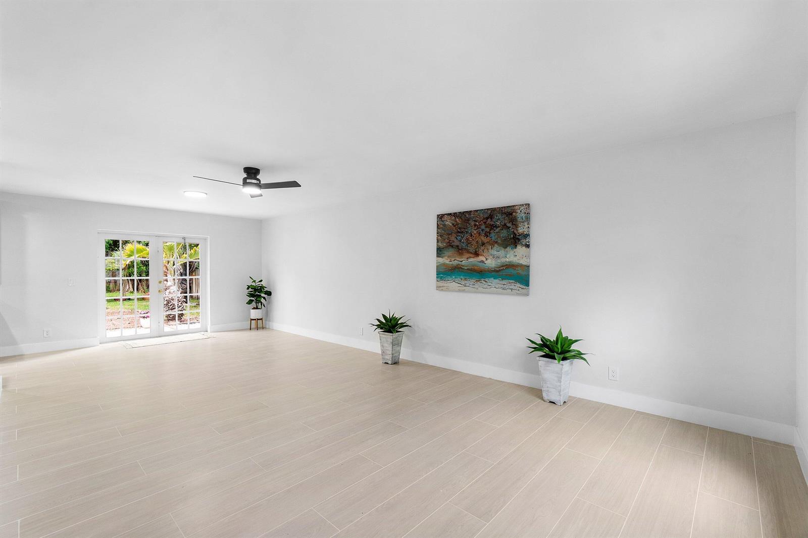 A bright, empty room with light-colored tile flooring, a ceiling fan, and French doors — 5119 Oak Hill Road, Delray Beach FL 33484, DELRAY BEACH, FL