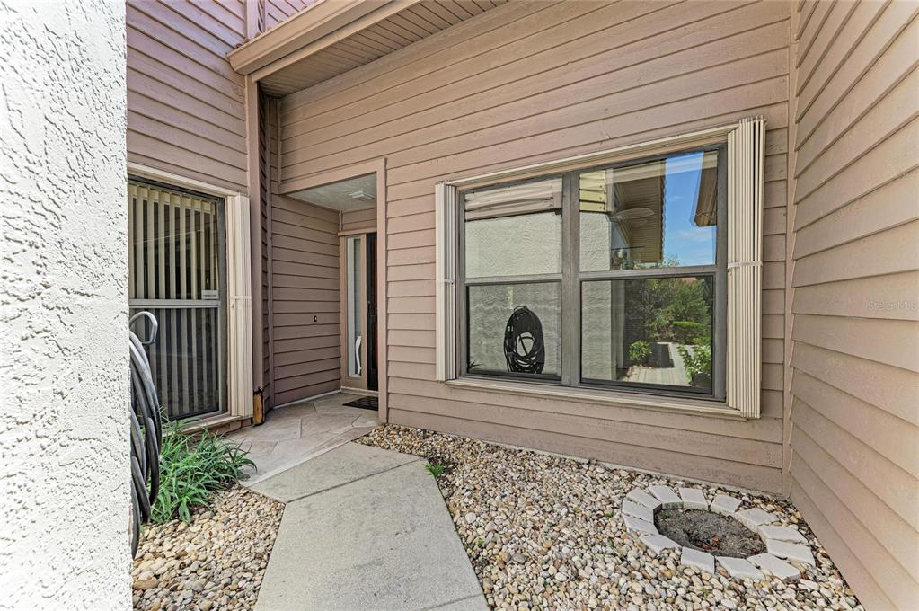 A tan-sided house exterior features a concrete walkway leading to a recessed front entryway — 3946 WILSHIRE CIRCLE E UNIT 168, SARASOTA, FL