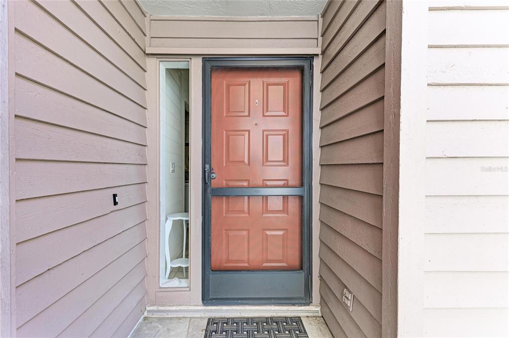 A front entryway features a red door with a screen door and a side window — 3946 WILSHIRE CIRCLE E UNIT 168, SARASOTA, FL