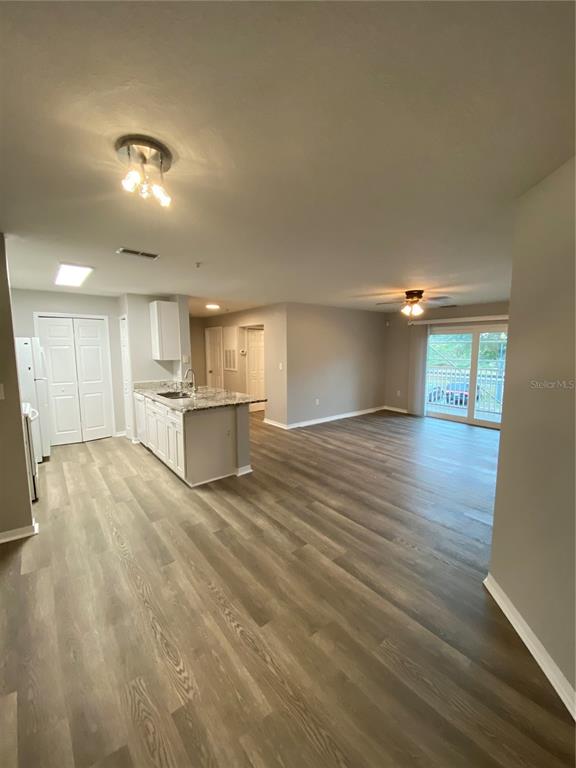 An open-concept kitchen with white cabinets and a breakfast bar overlooks a spacious living area — 5479 VINELAND ROAD UNIT 9213, ORLANDO, FL