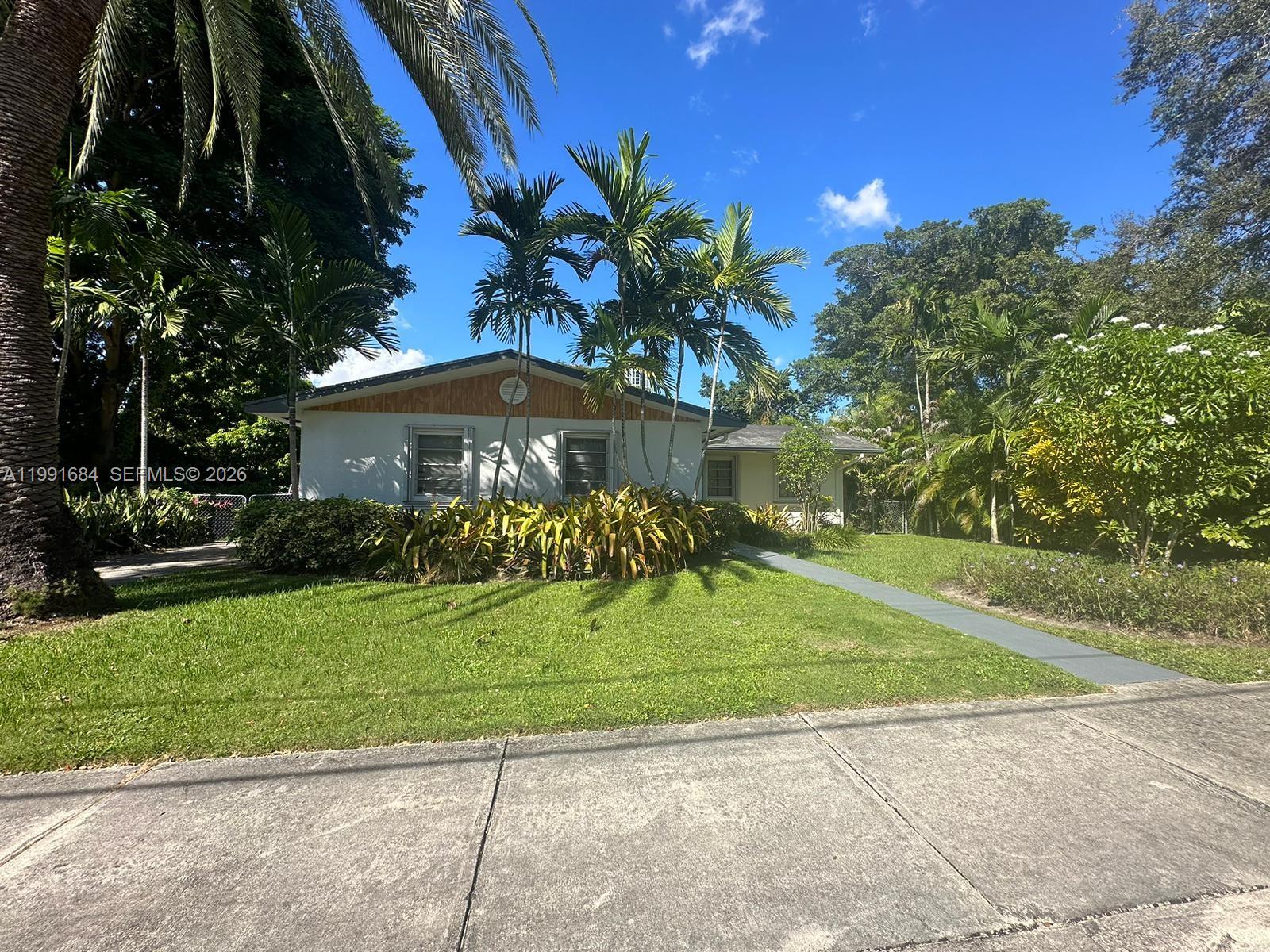 A single-story house with a white exterior, wood-paneled gable, and palm trees in the yard — 3755 Oak Ave, Miami FL 33133, MIAMI, FL