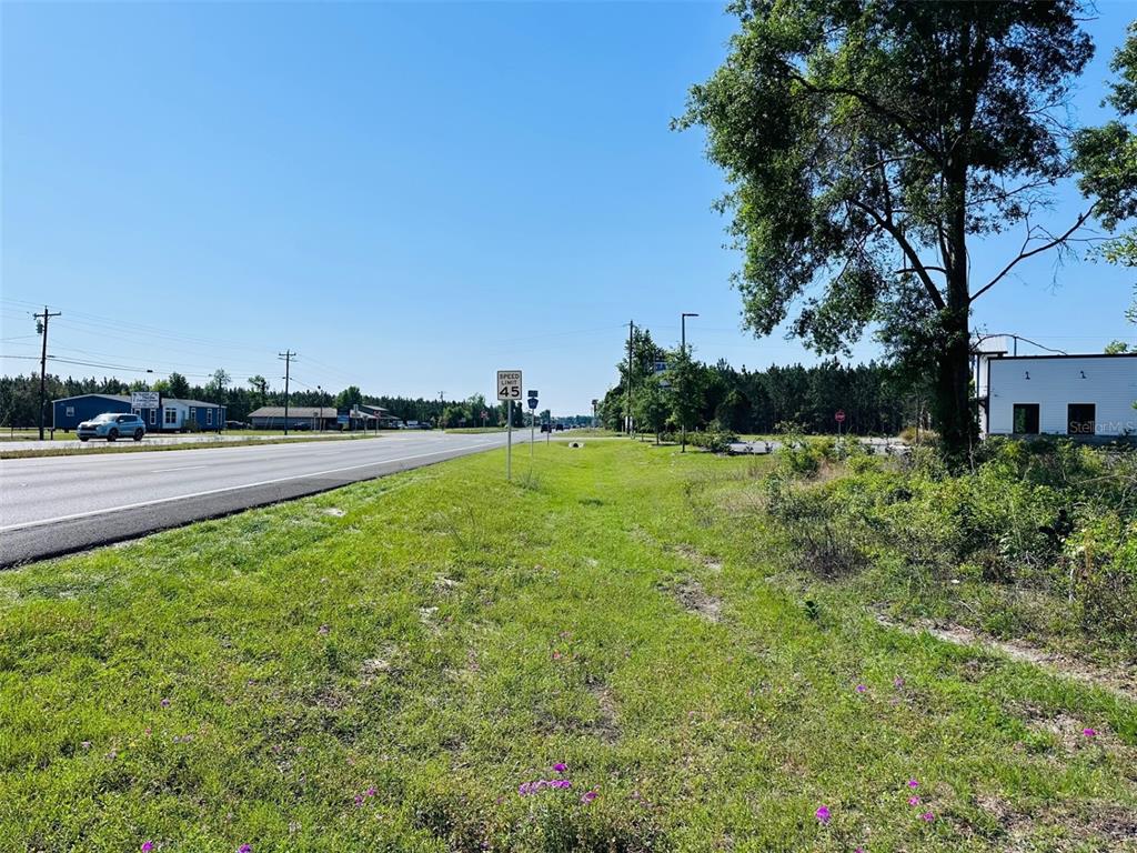 A grassy roadside lot sits next to a highway with a speed limit sign — 0 N YOUNG BOULEVARD, CHIEFLAND, FL