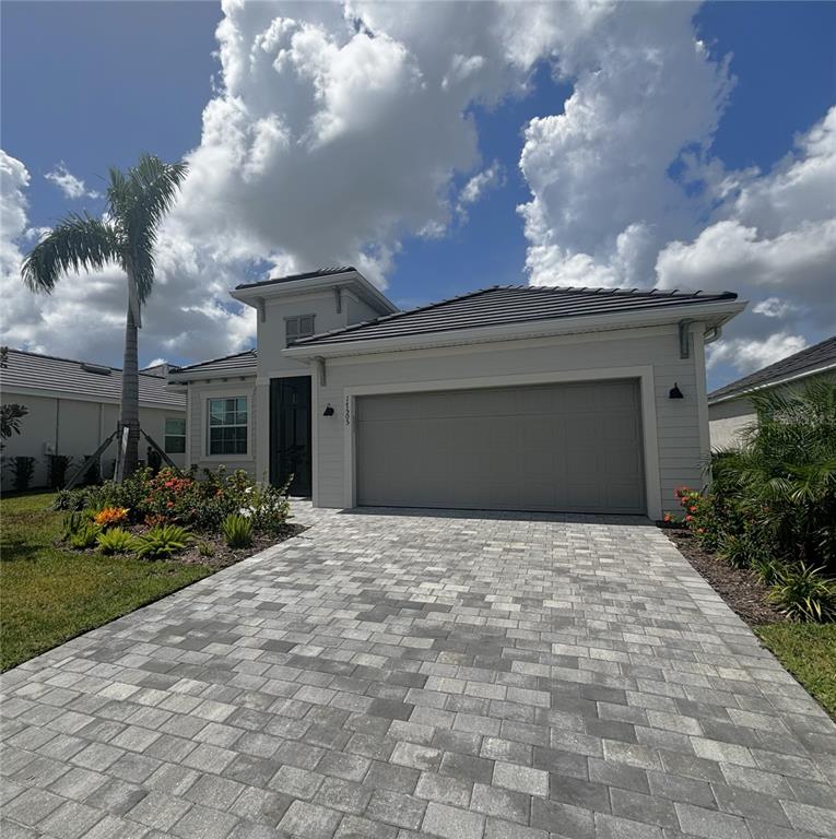 A single-story house with a paved driveway, a two-car garage, and a palm tree — 17435 JADESTONE COURT, VENICE, FL
