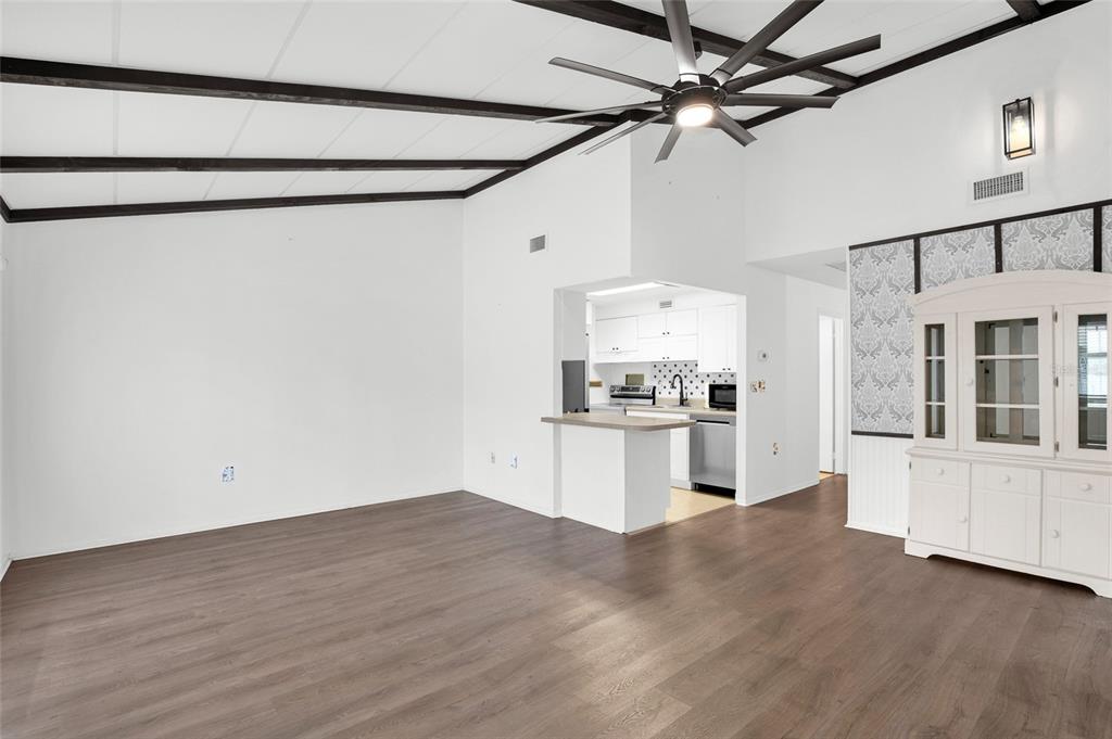 A living room with dark wood-look flooring, exposed ceiling beams, and an open kitchen — 6 COUNTRY CLUB DRIVE UNIT 6A, NEW SMYRNA BEACH, FL