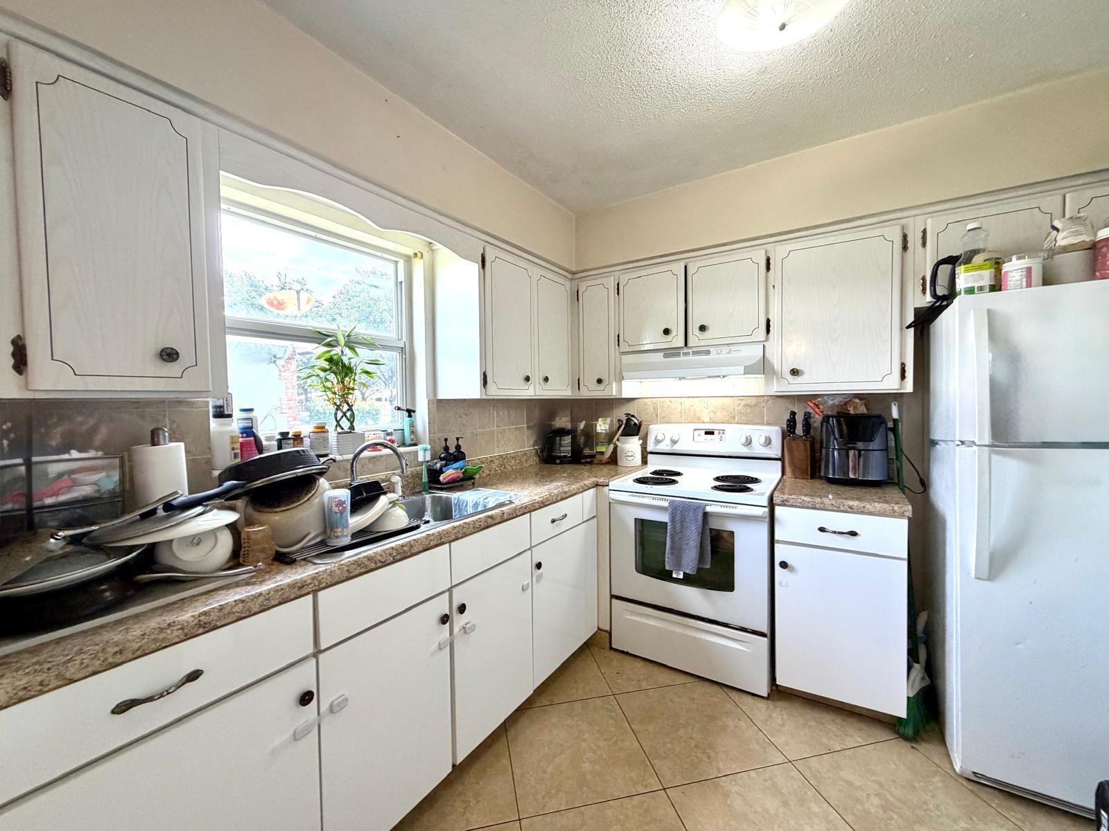 A kitchen features white cabinets, laminate countertops, a white stove, and a white refrigerator — 4731 NE 21st Terrace # 2, Lighthouse Point FL 33064, LIGHTHOUSE POINT, FL