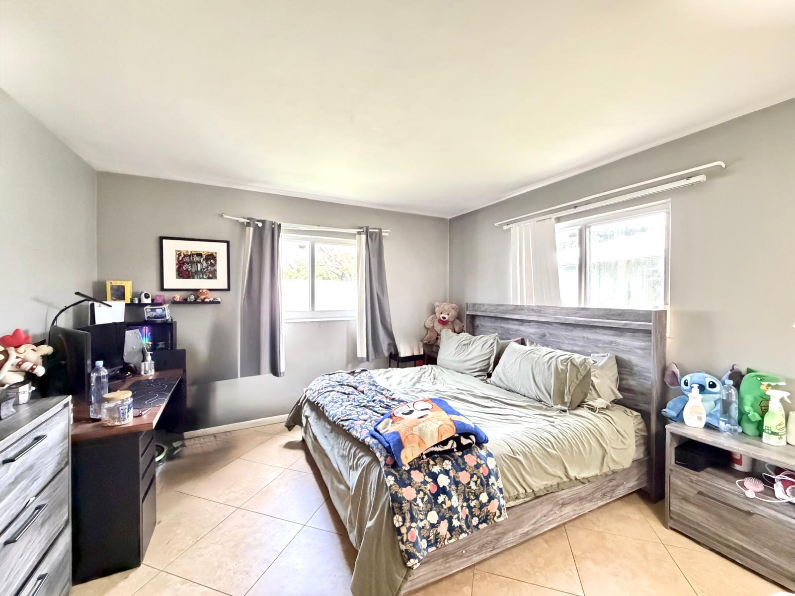 A bedroom features a bed with a grey wooden headboard, a desk, and tiled flooring — 4731 NE 21st Terrace # 2, Lighthouse Point FL 33064, LIGHTHOUSE POINT, FL