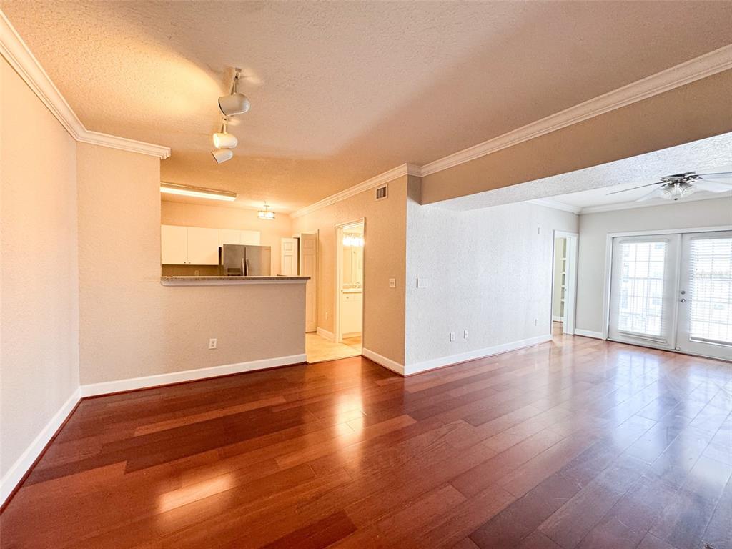 An open-concept living area features hardwood floors, a kitchen pass-through, and glass patio doors — 202 E SOUTH STREET UNIT 4039, ORLANDO, FL