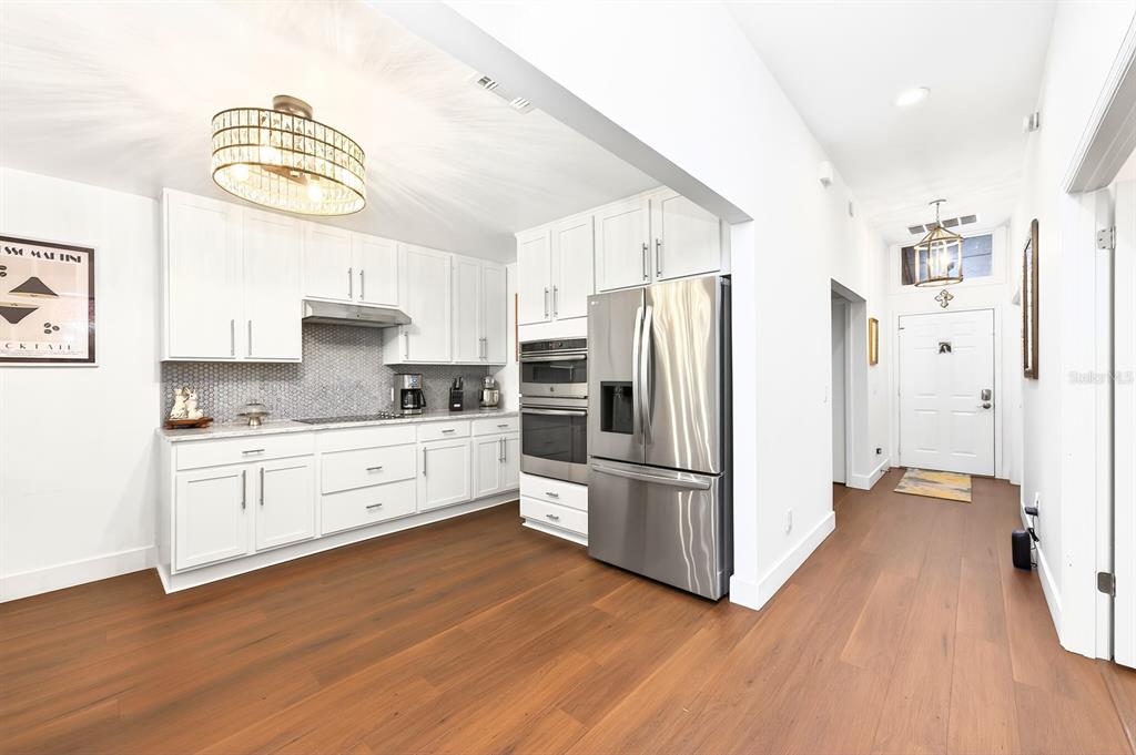 A modern kitchen features white cabinets, stainless steel appliances, and wood flooring — 314 SAND TRAP COVE, LONGWOOD, FL