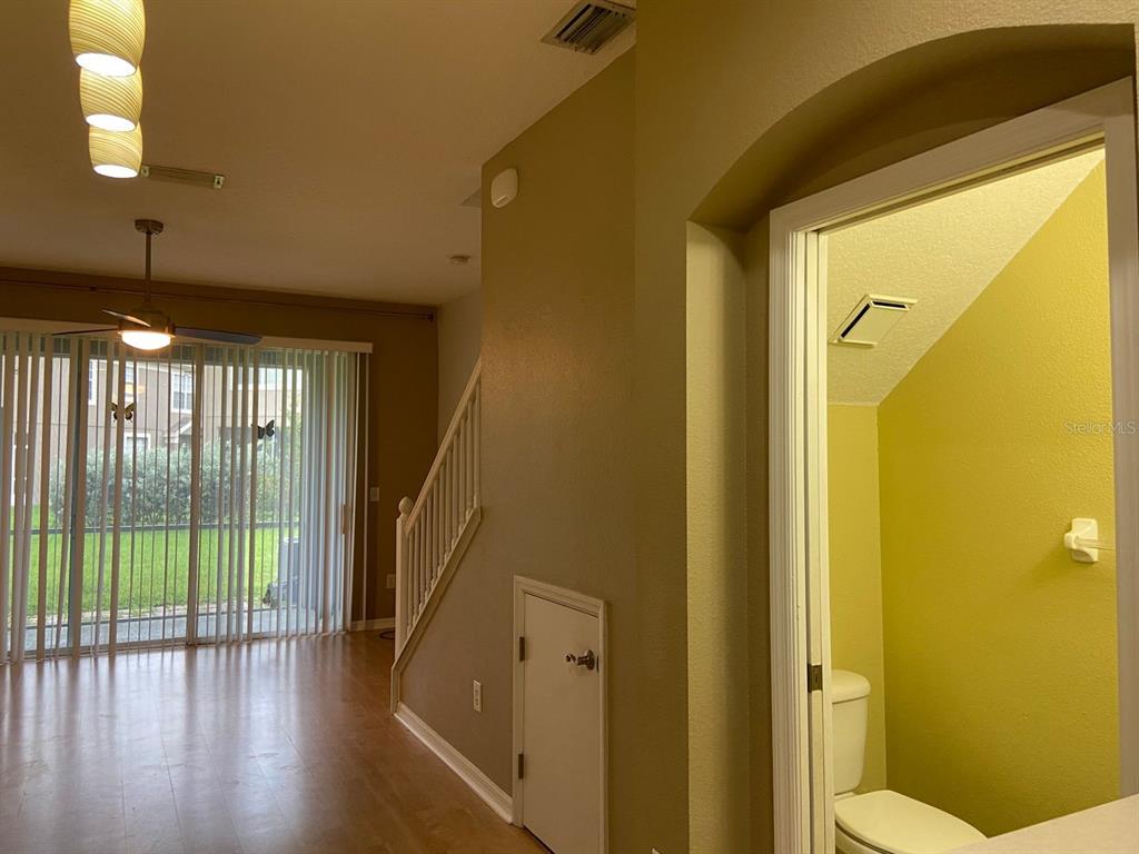 A room with wood flooring, a staircase, sliding glass doors, and an adjacent small bathroom — 11221 WINDSOR PLACE CIRCLE, TAMPA, FL