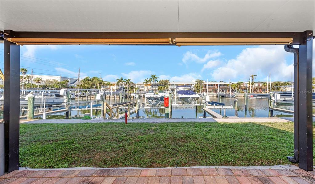A covered patio overlooks a boat slip and marina with several docked vessels — 2600 N PAULA DRIVE UNIT 12D, DUNEDIN, FL